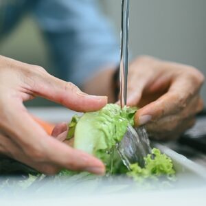 man washing lettuce with clean water from tap